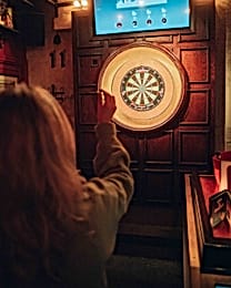 A woman aims to throw a dart at a dart board