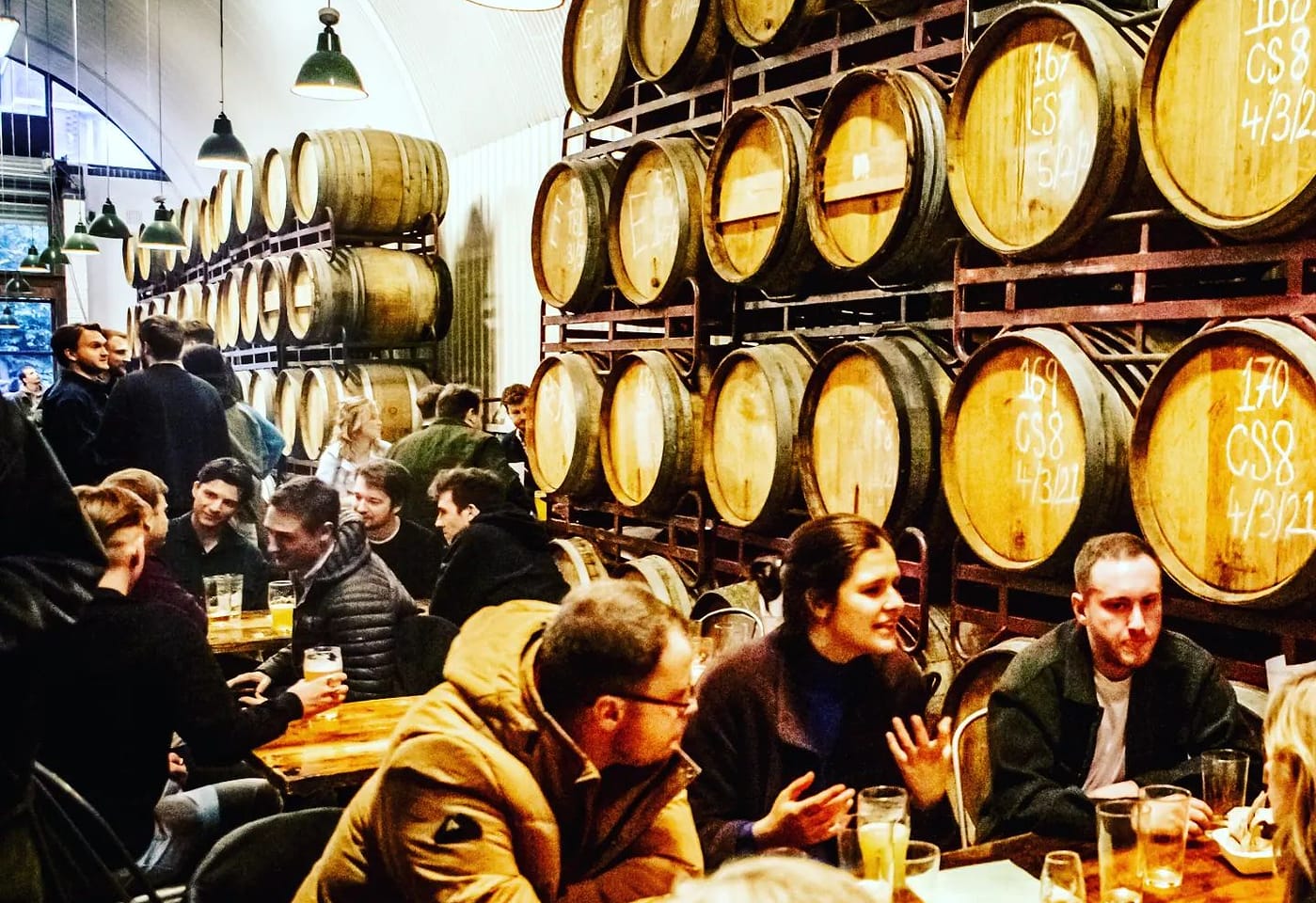 people seated by the barrels in the barrel project taproom in bermondsey london