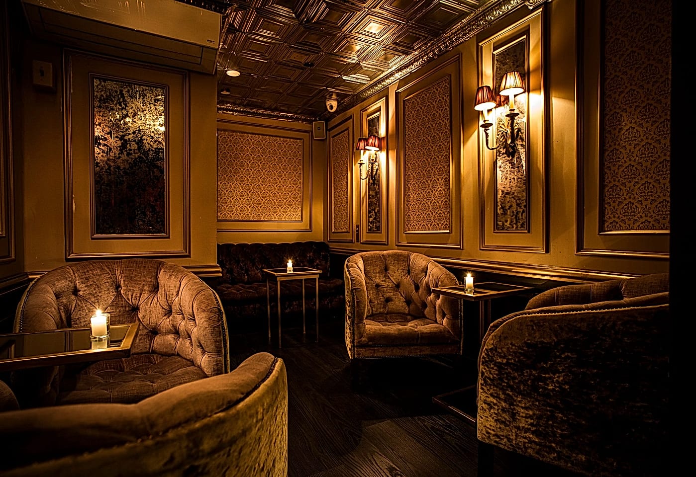 A dimly-lit room with elegant chairs at The Raines Law Room Chelsea, a bar for celebrating 21st birthdays in New York.