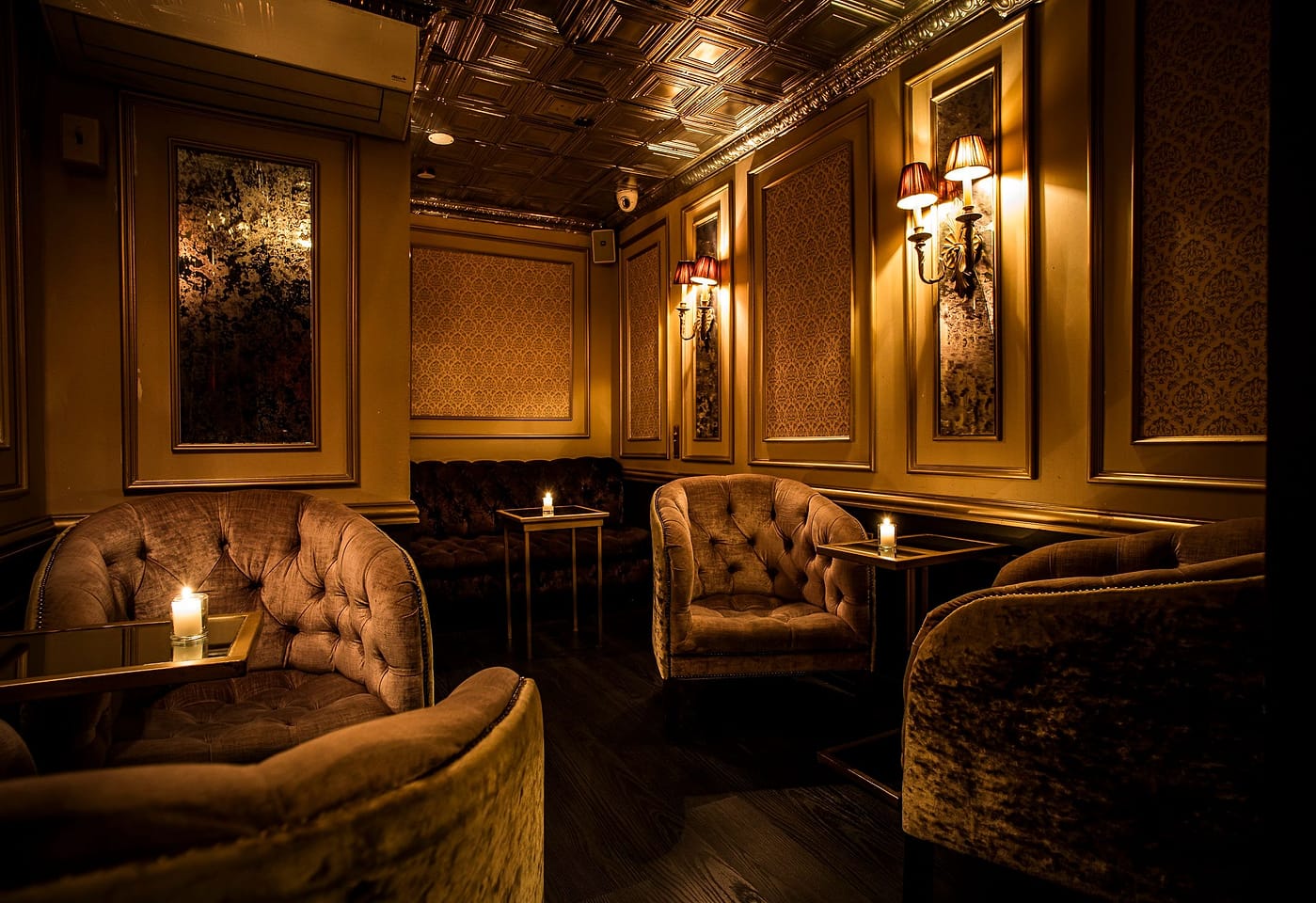 A dimly-lit room with elegant chairs at The Raines Law Room Chelsea, a bar for celebrating 21st birthdays in New York.