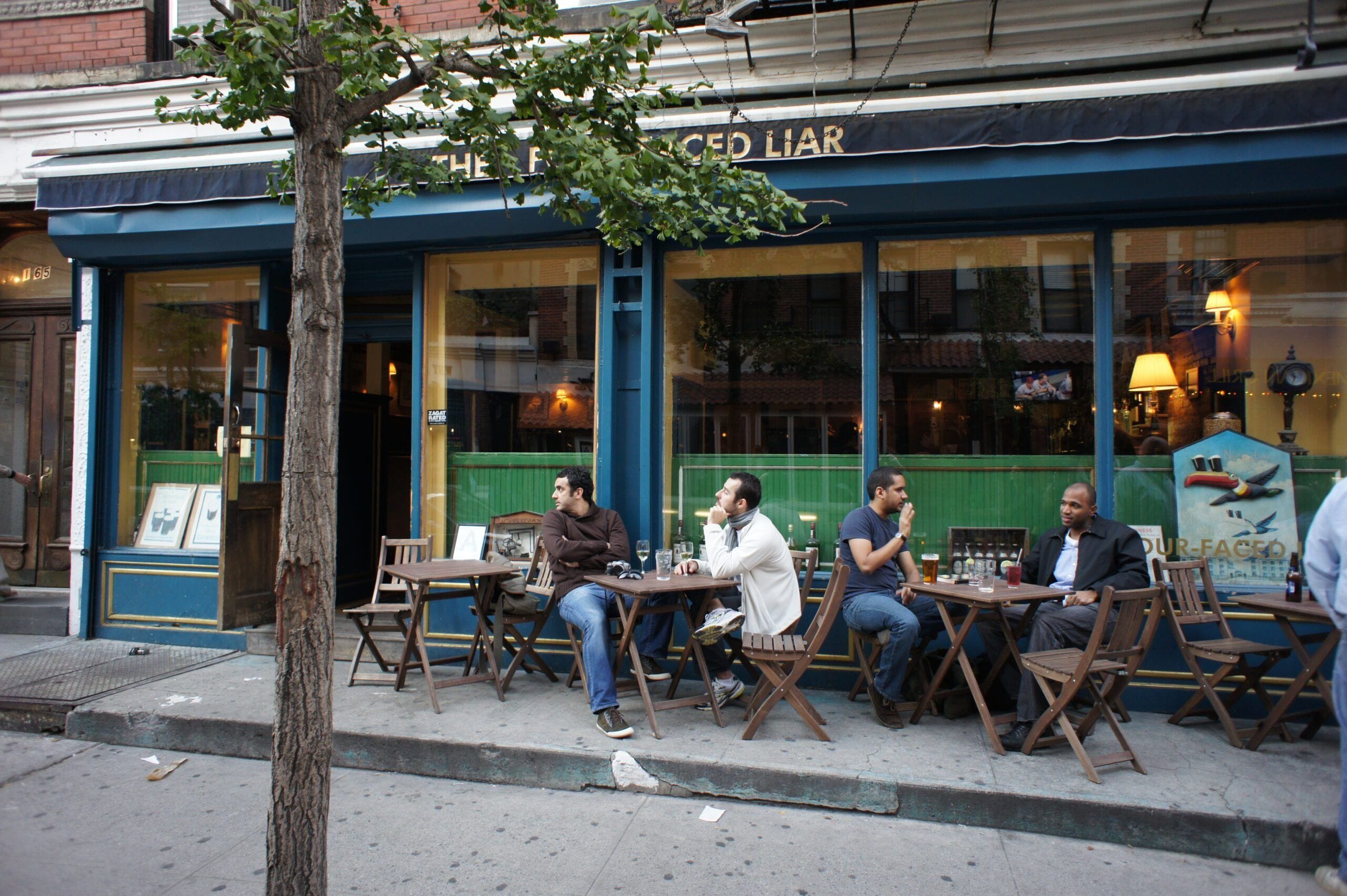 people sitting outside the four faced liar west village bar nyc